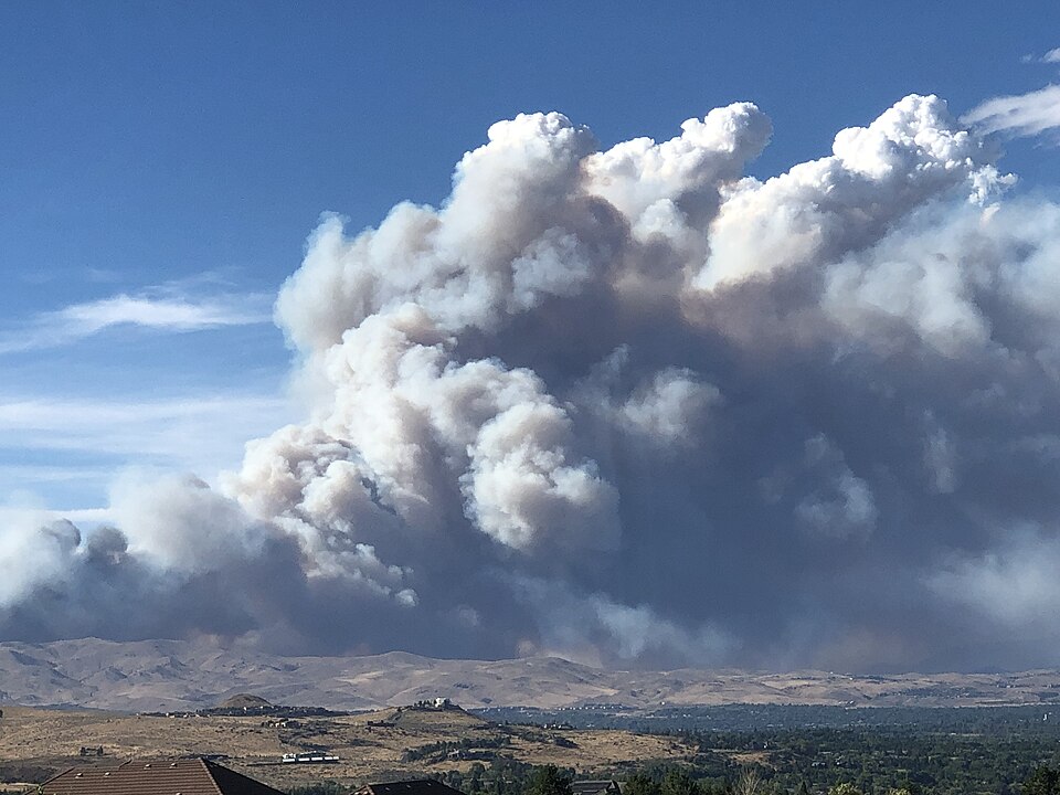 A large column of wildfire smoke rising over Peavine Mountain from the Hawk Fire